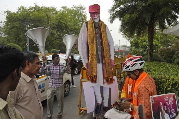 A Bharatiya Janta Party supporter prepares to offer prayers to the cut-out of Indian Prime Minister Narendra Modi outside their party headquarters in New Delhi, India, Tuesday, June 4, 2024. India began counting more than 640 million votes Tuesday in the world’s largest democratic exercise, which was widely expected to return Prime Minister Narendra Modi to a third term after a decade in power. (AP Photo/Manish Swarup)