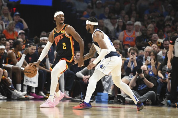 Oklahoma CIty Thunder guard Shai Gilgeous-Alexander, left, looks for an opening past Dallas Mavericks gurd Jaden Hardy, right, in the first half of an NBA basketball game, Sunday, April 14, 2024, in Oklahoma City. (AP Photo/Kyle Phillips)
