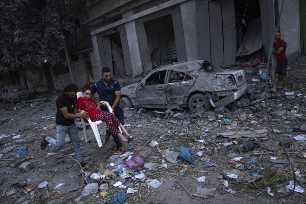Palestinians walk amid the rubble following Israeli airstrikes that razed swaths of a neighborhood in Gaza City, Tuesday, Oct. 10, 2023. (AP Photo/Fatima Shbair)