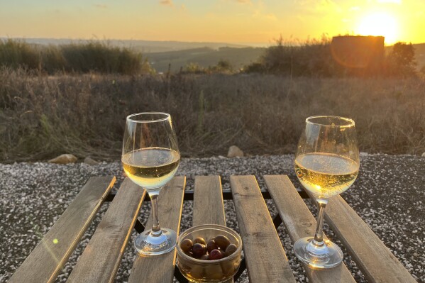 Glasses of Vinho Verde and local olives appear at sunset outside an old windmill-turned-Airbnb in the hills above Lourinhã, Portugal on Sept. 12, 2023, (Kristen de Groot via AP)