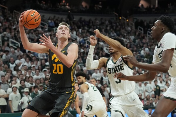 Iowa forward Payton Sandfort (20) attempts a layup as Michigan State guard Jaden Akins (3) defends during the first half of an NCAA college basketball game, Tuesday, Feb. 20, 2024, in East Lansing, Mich. (AP Photo/Carlos Osorio)