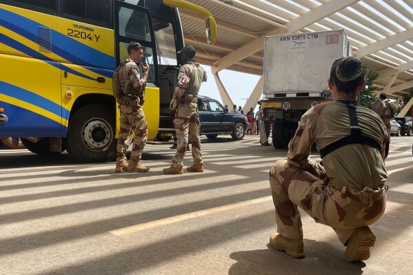 French soldiers assist mostly French nationals in a bus waiting to be airlifted back to France on a French military aircraft, at the international Airport in Niamey, Niger, Tuesday, Aug. 1, 2023. The French Foreign Ministry in Paris cited recent violence that targeted the French Embassy as one of the reasons for the evacuation. The decision comes during a deepening crisis sparked by the coup last week against Niger's democratically elected president, Mohamed Bazoum. (AP Photo/Sam Mednick)