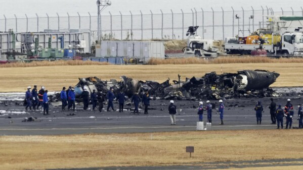 Police and Firefighters gather around the burn-out Japanese coast guard aircraft at Haneda airport on Wednesday, Jan. 3, 2024, in Tokyo, Japan. (Kyodo News via AP)