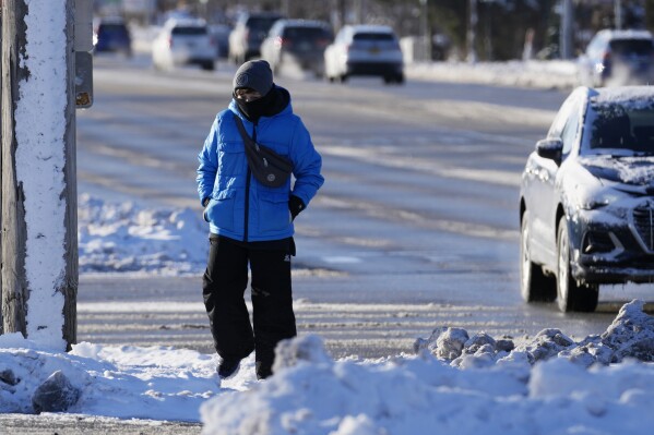 A pedestrian is huddled as she crosses a street in Buffalo Grove, Illinois, Sunday, January 14, 2024. A wind chill warning is in effect as dangerous cold conditions continue in the Chicago area.  (AP Photo/Nam Wai. Ha)