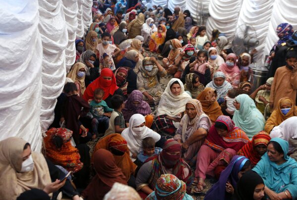 FILE - In this Saturday, April 10, 2021, file photo, women wait to receive food assistance for the upcoming Muslim fasting month of Ramadan, in Lahore, Pakistan. Muslims are facing their second Ramadan in the shadow of the pandemic. Many Muslim majority countries have been hit by an intense new coronavirus wave. While some countries imposed new Ramadan restrictions, concern is high that the month’s rituals could stoke a further surge. (AP Photo/K.M. Chaudary)