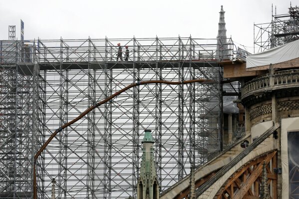 Workers walk through a scaffolding at Notre Dame cathedral, Friday, July 10, 2020 in Paris. Notre Dame Cathedral will be rebuilt just the way it stood before last year's devastating fire. (AP Photo/Thibault Camus)