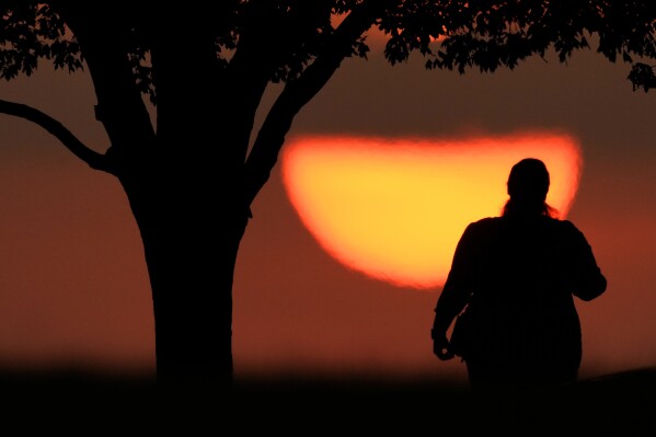 FILE - A woman watches the sun set on a hot day, Aug. 20, 2023, in Kansas City, Mo. A new study on Tuesday, May 14, 2024, finds that the broiling summer of 2023 was the hottest in the Northern Hemisphere in more than 2,000 years. (Ǻ Photo/Charlie Riedel, File)