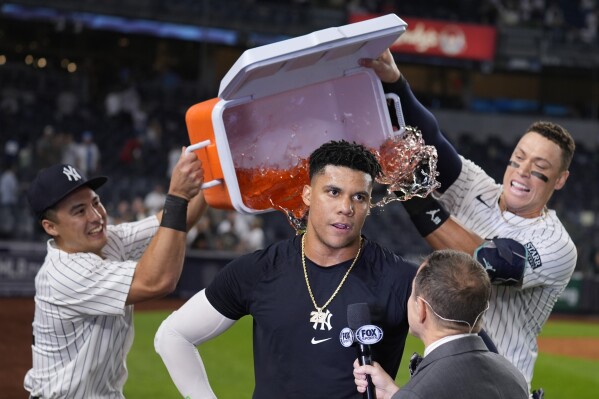 New York Yankees' Anthony Volpe, left, and Aaron Judge, right, douse Juan Soto, center, after he hit the winning base hit during the 10th inning of a baseball game against the Boston Red Sox at Yankee Stadium, Thursday, Sept. 12, 2024, in New York. (AP Photo/Seth Wenig)