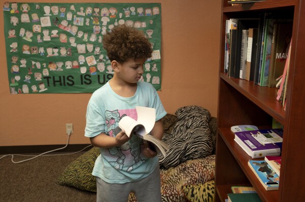 Shean Sutjin-Osby, 7, looks over books in the library at the African American Family and Cultural Center, in Oroville, Calif., Feb. 8, 2024. A measure aimed at transforming how California spends money on mental health will go before voters in March as the state continues to grapple an unabated homelessness crisis. The 14-year-old community center, that offers a variety of programs including after school programs, art classes, anger management sessions could be forced to close if it loses it's funding from Butte County. (AP Photo/Rich Pedroncelli)