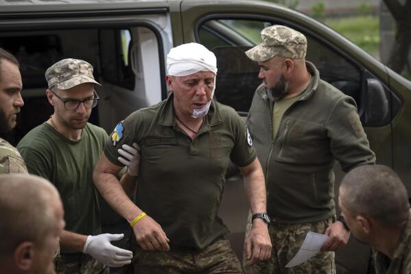 Ukrainian soldiers help their wounded fellow at a medical stabilisation point near Bakhmut, Donetsk region, Ukraine, Wednesday, May 24, 2023. (AP Photo/Efrem Lukatsky)