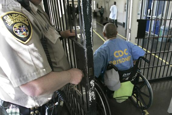 FILE - A wheelchair-bound inmate wheels himself through a checkpoint at the California Medical Facility in Vacaville, Calif., on April 9, 2008. A prominent California medical school has apologized for conducting unethical experimental medical treatments on 2,600 incarcerated men in the 1960s and 1970s. (AP Photo/Rich Pedroncelli, File)
