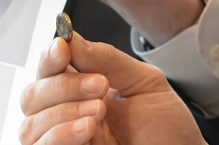 FILE - In this Wednesday, Dec. 21, 2016 file photo, a lawyer holds a battery that was removed from a toddler's esophagus at a news conference in Jacksonville, Fla. A study published Friday, April 12, 2019 in the journal Pediatrics found a sharp increase in emergency room visits involving swallowed objects by kids under age 6. (Bruce Lipsky/The Florida Times-Union via AP)