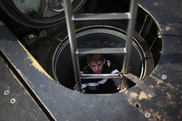 A sailor descends into a French Rubis-class submarine at the Toulon naval base in southern France, Monday, April 15, 2024. (AP Photo/Daniel Cole)