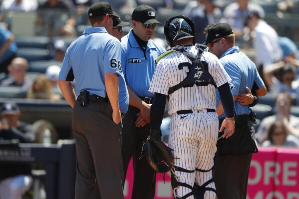 Umpire Mike Muchlinski, right, is attended to after being hit by a foul ball during the first inning of a baseball game between the New York Yankees and the Houston Astros, Sunday, June 26, 2022, in New York. (AP Photo/Noah K. Murray)