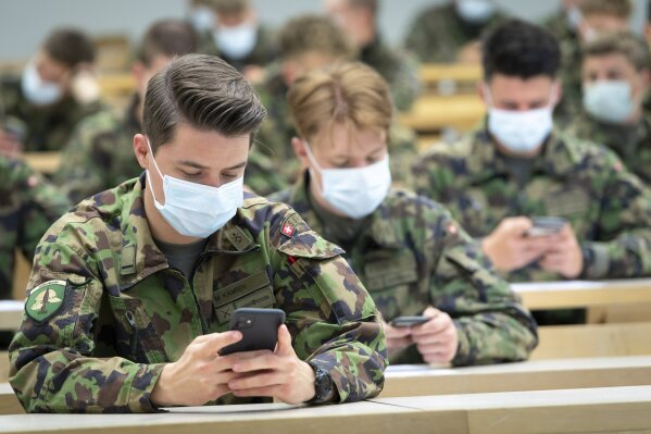 Soldier of the Swiss army wearing a protective face mask hold smartphones with an app using Decentralized Privacy-Preserving Proximity Tracing (DP-3T) during a test with 100 soldiers in the military compound of Chamblon near Yverdon-les-Bains, Switzerland, Thursday, April 30, 2020. The race by governments to develop mobile tracing apps in order to contain infections after lockdowns ease is focusing attention on privacy. The debate is especially urgent in Europe, where academics and civil liberties activists are pushing for solutions that protect personal data. (Laurent Gillieron/Keystone via AP)