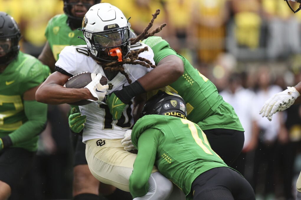 Colorado wide receiver Xavier Weaver, left, is tackled by Oregon defensive back Trikweze Bridges, bottom, and linebacker Emar'rion Winston, top, during the second half of an NCAA college football game, Saturday, Sept. 23, 2023, in Eugene, Ore. Oregon won 42-6. (AP Photo/Amanda Loman)