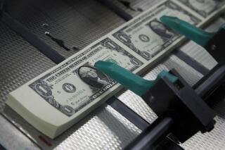 FILE - New $1 bills with the signatures of U.S. Treasurer Jovita Carranza and Treasury Secretary Steven Mnuchin are cut and stacked at the Bureau of Engraving and Printing in Washington, Nov. 15, 2017. More workers are following experts' advice in saving for retirement, even when finances feel precarious. (AP Photo/Jacquelyn Martin, File)
