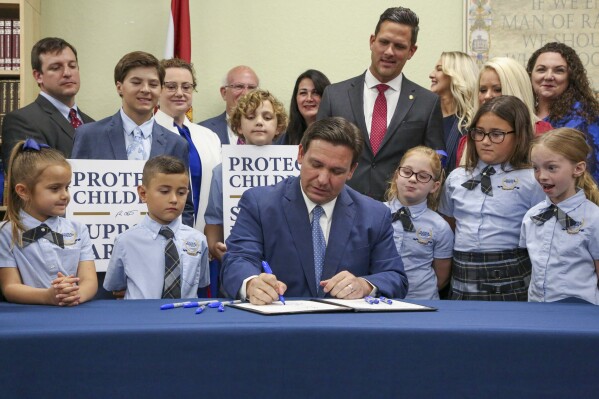 FILE - Florida Gov. Ron DeSantis signs the Parental Rights in Education bill at Classical Preparatory school, March 28, 2022, in Shady Hills, Fla. Top officials at a Florida school district ordered the removal of all books and material containing LBGTQ+ characters and themes from classrooms and campus libraries, saying that was needed to conform to a state law backed by DeSantis that critics have dubbed “Don't Say Gay,” according to a district memo obtained under a public information request by the Florida Freedom to Read Project. The nonprofit group, which opposes the law, provided the memo to The Associated Press on Wednesday, Sept. 27, 2023. (Douglas R. Clifford/Tampa Bay Times via AP, File)