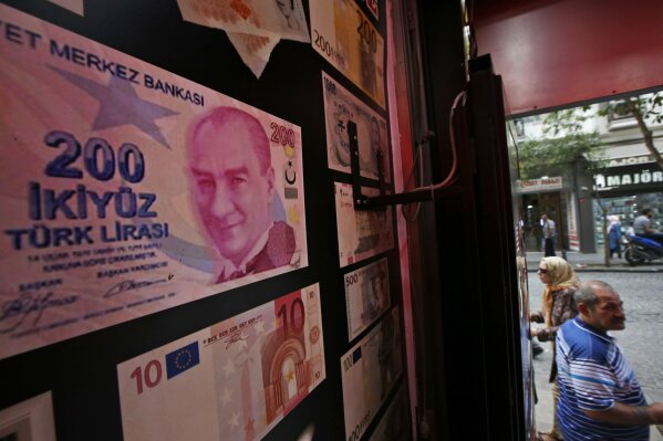 FILE-In this Friday, Aug. 17, 2018 file photo, an oversized copy of a 200 Turkish lira banknote, featuring a photo of modern Turkey's founder Mustafa Kemal Ataturk decorates a currency exchange shop in Istanbul. Turkey's currency dropped to an all-time low against the dollar on Thursday Aug. 6, 2020, as the global recession created by the coronavirus pandemic brings to the fore weaknesses in the country's economy.(AP Photo/Lefteris Pitarakis, File)