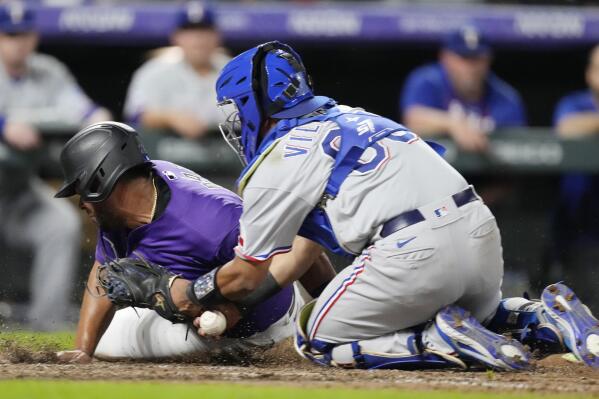 Texas Rangers catcher Meibrys Viloria, right, loses the ball after tagging out Colorado Rockies' Elias Diaz as he tries to score in the eighth inning of a baseball game Tuesday, Aug. 23, 2022, in Denver. (AP Photo/David Zalubowski)