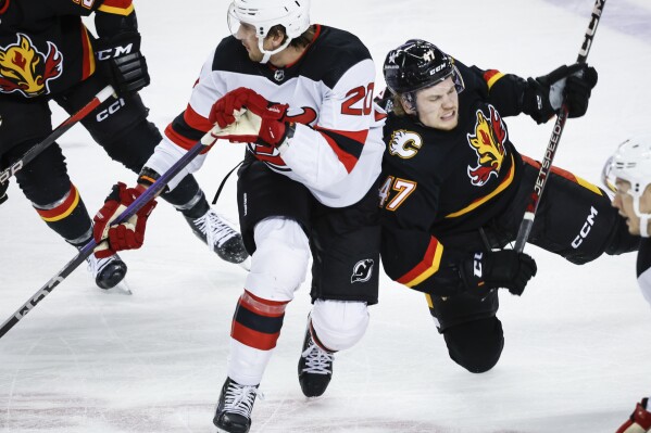 New Jersey Devils forward Michael McLeod (20) checks Calgary Flames forward Connor Zary (47) during the second period of an NHL hockey match in Calgary, Alberta, Saturday, Dec. 9, 2023. (Jeff McIntosh/The Canadian Press via 鶹ýapp)