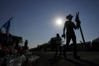 Roberto Marquez coloca una cruz de madera en un monumento conmemorativo improvisado en el sitio en el que las autoridades descubrieron a 53 migrantes muertos en un tractocamión abandonado, el 30 de junio de 2022, en San Antonio, Texas. (AP Foto/Eric Gay)