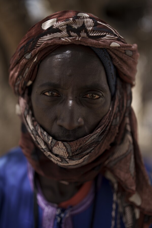 Suleymane Ba stands for a portrait at a local market near a water station known as Bem Bem, in the Matam region of Senegal, Wednesday, April. 19, 2023. For the 43-year-old herder, pastoralism is an inherited tradition that has its advantages and disadvantages. When you have grassland and your cattle is protected, you are able to feed yourself with milk and, if necessary, to sell a sheep, goat or cow. When there is a lack of water "this causes harm to the livestock", he says. (AP Photo/Leo Correa)