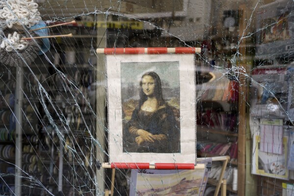 A poster of the Mona Lisa hangs in a shattered storefront window at the site where a missile launched from Iran struck in Haifa, Israel, Sunday, June 22, 2025. (AP Photo/Baz Ratner)