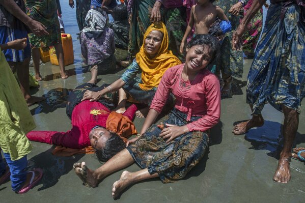 
              Rohingya Muslim women, who crossed over from Myanmar into Bangladesh, wail as a relative lies unconscious after the boat they were traveling in capsized minutes before reaching shore at Shah Porir Dwip, Bangladesh, Thursday, Sept. 14, 2017. Nearly three weeks into a mass exodus of Rohingya fleeing violence in Myanmar, thousands were still flooding across the border Thursday in search of help and safety in teeming refugee settlements in Bangladesh. The woman survived. (AP Photo/Dar Yasin)
            