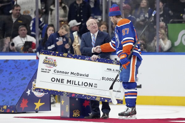 Edmonton Oilers' Connor McDavid (97) is presented with an oversized check for $ 1 million after winning the NHL All-Star hockey skills competition in Toronto, Friday, Feb. 2, 2024. (Nathan Denette/The Canadian Press via AP)