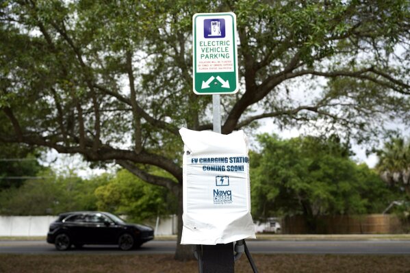 A parking area with charging stations for electric vehicles at a public park is seen Thursday, April 1, 2021, in Orlando, Fla. As part of an infrastructure proposal by the Biden administration, $174 billion will be set aside to build 500,000 electric vehicle charging stations, electrify 20% of school buses and electrify the federal fleet, including U.S. Postal Service vehicles.(AP Photo/John Raoux)