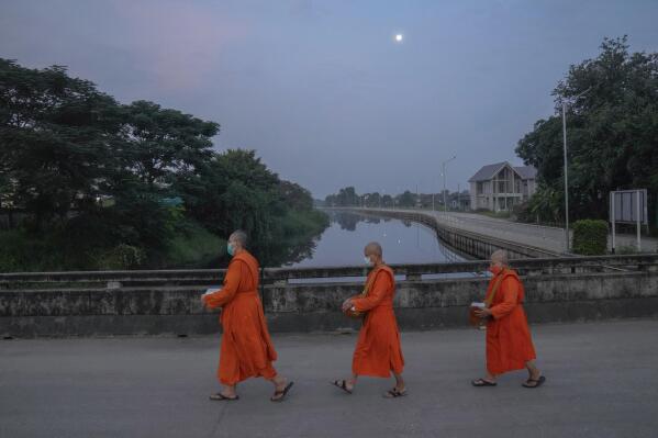 From left, Bhikkhuni Dhammavanna, Bhikkhuni Dhammaparipunna and Bhikkhuni Dhammasumana walk to collect alms from devotees in Nakhon Pathom province on Sunday, Nov. 21, 2021. Women are banned from becoming monks in Thailand, where over 90% of the population is Buddhist. Historically, women could only become white-cloaked nuns often treated as glorified temple housekeepers. But dozens have traveled to Sri Lanka to receive full ordination. (AP Photo/Sakchai Lalit)