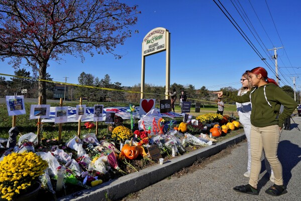 FILE - Community members look at a memorial outside Schemengees Bar & Grille about one week after a mass shooting, Nov. 3, 2023, in Lewiston, Maine. An independent commission investigating the mass shooting that left 18 people dead in Maine is scheduled to hear from the family of the shooter, Robert Card, for the first time on Thursday, May 15, 2024. (AP Photo/Matt York, File)