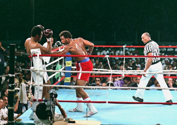 George Foreman, center, lands a body punch to Muhammad Ali during fight action in Zaire, Africa, Oct. 30, 1974. Referee Zack Clayton is at right.(AP Photo, File)