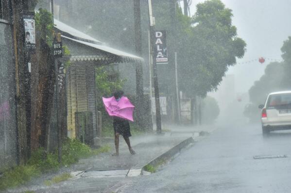 A woman fights Gale force winds in the Indian Ocean Island of Mauritius Wednesday Feb. 2, 2022. Forecasts say Tropical Cyclone Batsirai is increasing in intensity and is expected to pass north of the Indian Ocean island nation of Mauritius on Wednesday evening and make landfall in central Madagascar on Saturday afternoon.The Global Disaster Alert and Coordination System says Batsirai has been upgraded and classified as Category 4.(Beekash Roopun/L'express Maurice via AP)