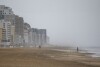 Beach-goers brave the weather and walk along the sand at the Virginia Beach Oceanfront on Friday, Sept. 22, 2023, as Tropical Storm Ophelia approaches in Virginia Beach, Va. The storm was gaining strength as it churned toward the North Carolina coast on Friday, promising a weekend of heavy rain and windy conditions throughout the mid-Atlantic. (Kendall Warner/The Virginian-Pilot via AP)