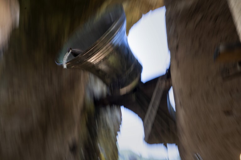 Roser Reixach, a student of the Vall d'en Bas School of Bell Ringers, performs playing a bronze bell at the church bell tower of the12th-century Sant Romà church, at the tiny village of Joanetes, about two hours north of Barcelona, Spain, Saturday, June 29, 2024. A school set up to revive the manual ringing of church bells has graduated its first class of 18 students after learning their ringing skills. (AP Photo/Emilio Morenatti)