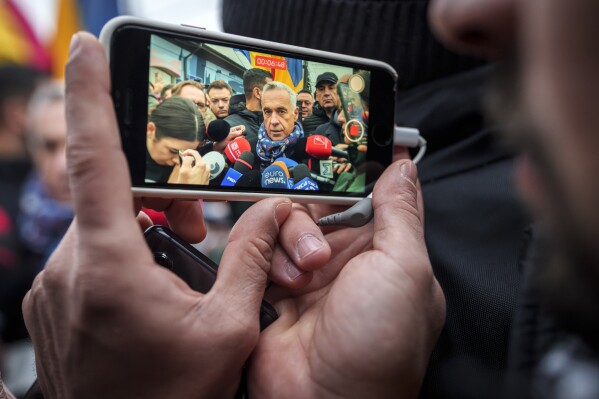A man records video of Calin Georgescu, an independent candidate for president who won the first round of presidential elections, speaking to media outside a closed voting station after Romania's Constitutional Court annulled the first round of presidential elections, in Mogosoaia, Dec. 8, 2024. (AP Photo/Vadim Ghirda, File)