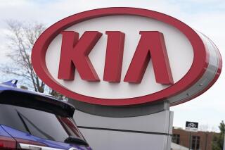 The company logo stands over a row of unsold 2021 Seltos models at a Kia dealership Sunday, Dec. 20, 2020, in Centennial, Colo.  Kia is recalling more than 440,000 vehicles in the U.S. for a second time to fix a problem that can cause engine fires. The automaker, Tuesday, May, 18, 2021,  also is telling owners to park them outdoors and away from structures because fires could happen when the engines aren’t running. The recall covers certain Optima sedans from 2013 through 2015 and Sorento SUVs from 2014 and 2015.   (AP Photo/David Zalubowski)