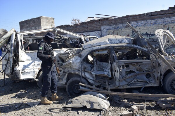 A police officer examines the damaged vehicles at the site of Tuesday's suicide bombing, in Bannu, in northwestern Pakistan, Wednesday, March 5, 2025. (AP Photo/Ijaz Muhammad)
