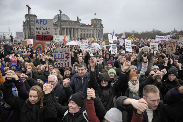 People hold hands in front of Germany's parliament Reichstag at a demonstration against the AfD party and right-wing extremism in Berlin, Germany, Saturday, Feb. 3, 2024 (AP Photo/Ebrahim Noroozi)