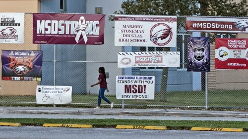 FILE - A student arrives for school at Marjory Stoneman Douglas High School during the one-year anniversary of the school shooting, Thursday, Feb. 14, 2019, in Parkland, Fla. The 2018 Parkland high school massacre will be reenacted with the firing of about 140 blanks on campus as part of families' lawsuits against the former sheriff's deputy they accuse of failing to stop the gunman, a judge ruled Wednesday, July 12, 2023. (Al Diaz/Miami Herald via AP)