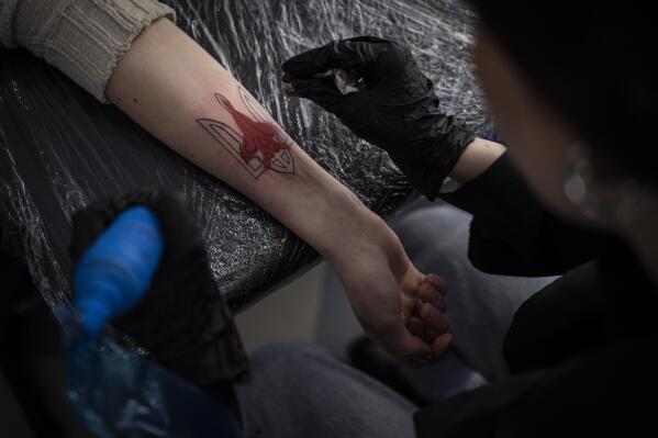 Ukrainian Natalia Tanchynets works on a patriotic-themed tattoo at her workshop in Lviv, Western Ukraine, Saturday, March 19, 2022. (AP Photo/Bernat Armangue)