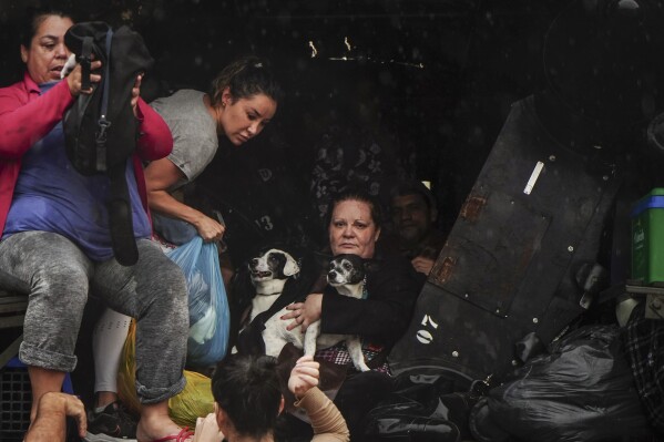 Bewoners en hun huisdieren evacueren een overstroomd gebied na zware regenval in Sao Sebastião do Cai, staat Rio Grande do Sul, Brazilië, donderdag 2 mei 2024. (AP Photo/Carlos Macedo)