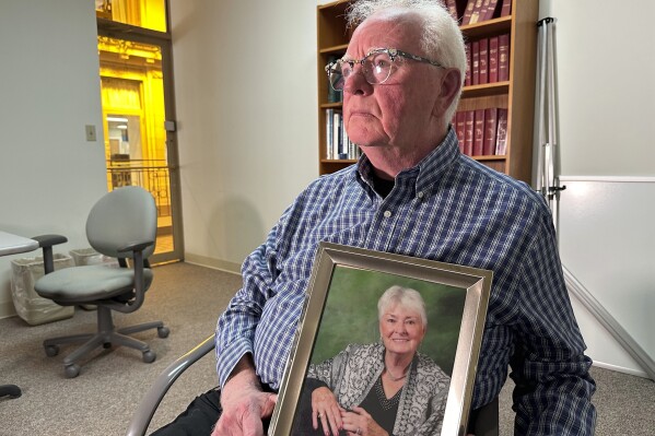 Michael Kruzich holds a photo of his late mother Donna during an interview Monday, April 15, 2024, in Lansing, Mich. Donna Kruzich was one of dozens of people in the U.S. who died after being injected with tainted steroids made by a specialty pharmacy in Massachusetts. Now, more than a decade later, the operator of the New England Compounding Center is returning to a Michigan court to be sentenced on involuntary manslaughter charges. (AP Photo/Mike Householder)