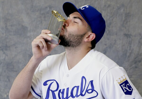 FILE - Kansas City Royals' Eric Hosmer kisses a replica World Series trophy as he poses for a photographer during photo day at spring training baseball Thursday, Feb. 25, 2016, in Surprise, Ariz. Hosmer announced his retirement from baseball Wednesday, Feb. 21, 2024, following a 13-year career that included winning four Gold Gloves and helping lead Kansas City to victory in the 2015 World Series.(AP Photo/Charlie Riedel, File)