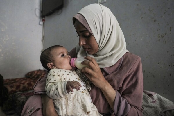 Rola Saqer feeds her baby Massa Mohammad Zaqout in her parents' home in Nuseirat refugee camp, central Gaza, Thursday, April 4, 2024. Zaqout was born Oct. 7, the day the Israel- Hamas war erupted. Mothers who gave birth that day fret that their 6-month-old babies have known nothing but brutal war, characterized by a lack of baby food, unsanitary shelter conditions and the crashing of airstrikes. (AP Photo/Abdel Kareem Hana)