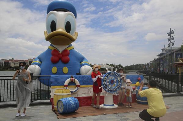 FILE - Visitors pose for photos outside the Disney Resort theme park in Shanghai on June 30, 2022. Shanghai Disneyland was closed and visitors temporarily kept in the park for virus testing, Monday, Oct. 31, 2022, the city government announced, while social media posts said some amusements kept operating for guests who were blocked from leaving. (AP Photo/Chen Si, File)