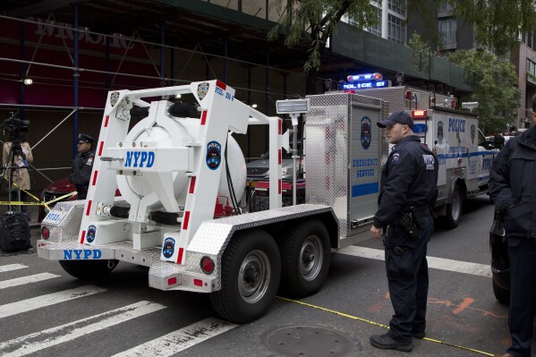 FILE - A police truck tows a total containment vessel to a post office in midtown Manhattan to dispose of a suspicious package, Friday, Oct. 26, 2018, in New York. Two law enforcement officials say a package closely resembling parcels sent to critics of President Donald Trump were found at the postal facility in Manhattan. A committed conspiracy theorist from Florida mailed pipe bombs to CNN, Hillary Clinton and several other top Democrats; the man’s social media feed was littered with posts about child sacrifice and chemtrails — the debunked claim that airplane vapor clouds contain chemicals or biological agents being used to control the population. (AP Photo/Mark Lennihan, File)