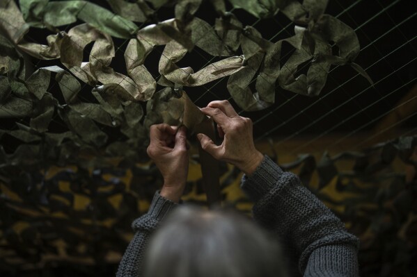 A volunteer makes camouflage netting at a facility producing equipment for Ukrainian soldiers in kyiv, Ukraine, Monday, April 22, 2024. A recently approved $61 billion U.S. aid package could prevent Ukraine from losing its war against Russia.  But victory will be a long task.  (AP Photo/Francisco Seco)